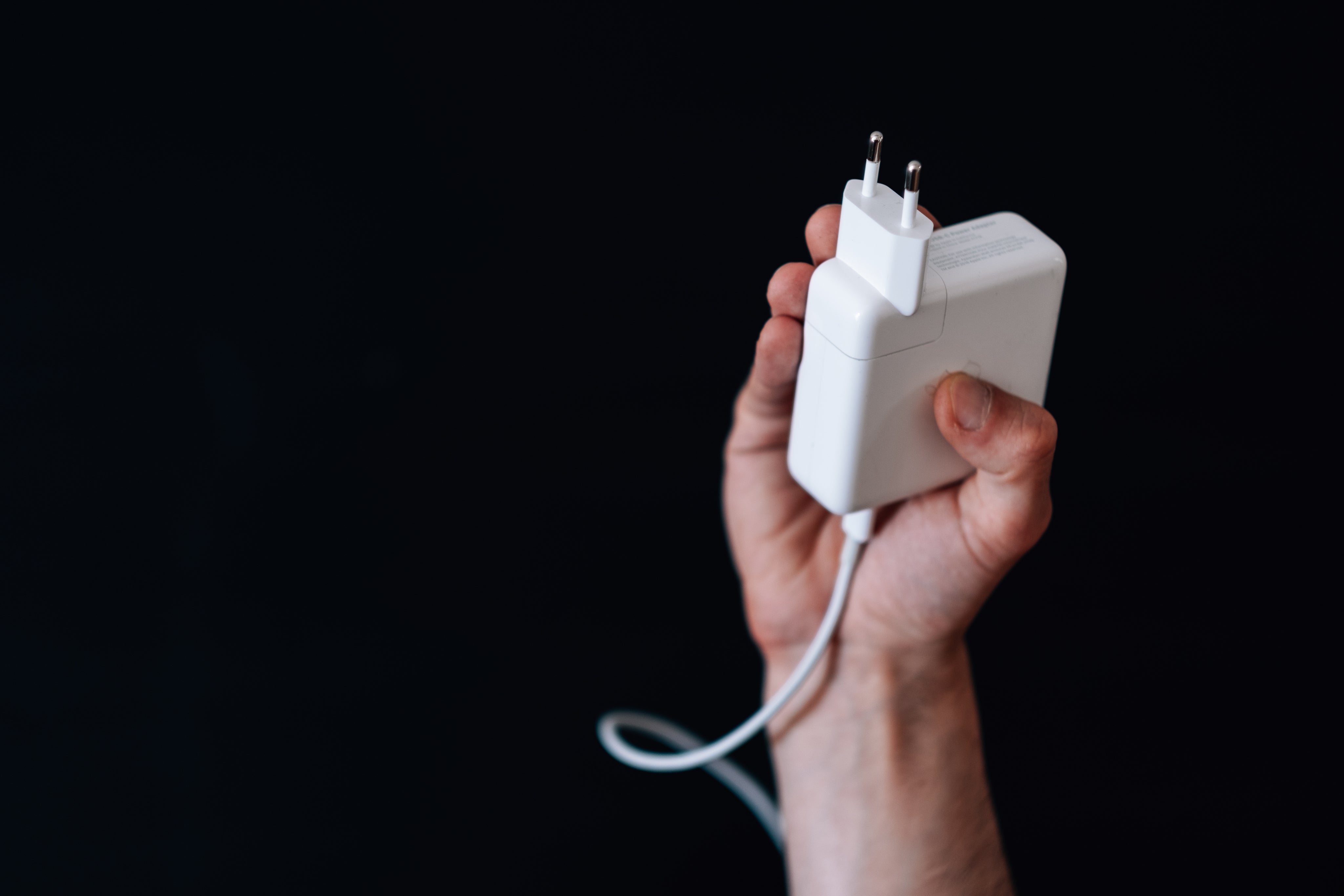 hand-holds-up-a-white-square-computer-charger.jpg